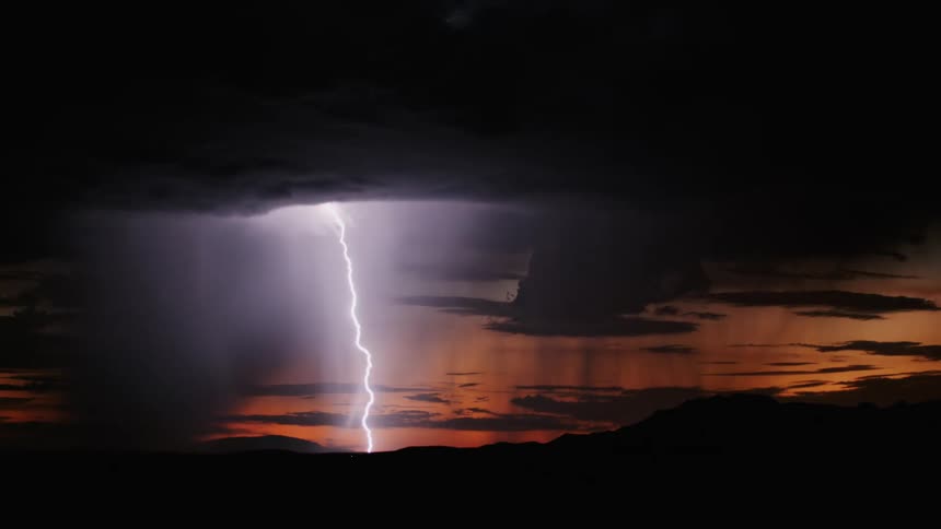 Black clouds with strong gusts of thunder and the sun in the background