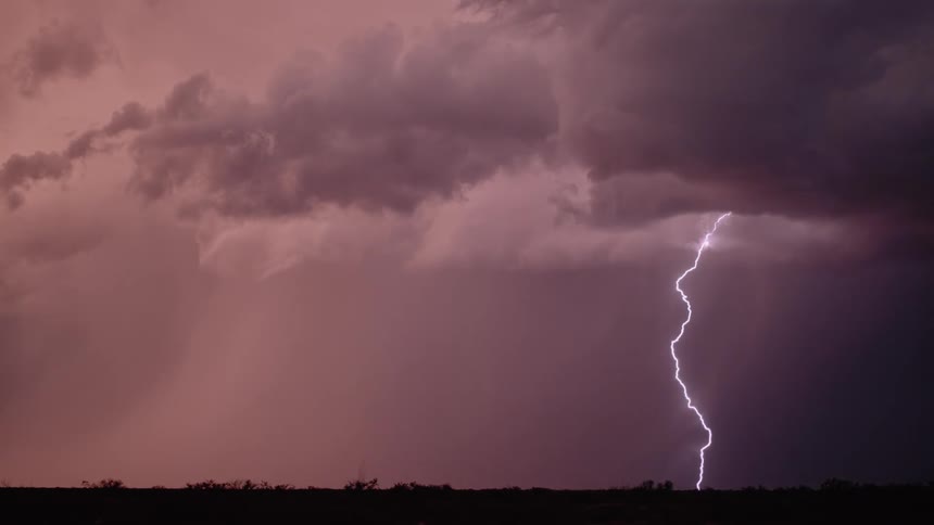 Lightning flashes across a dark pink sky and strikes the ground