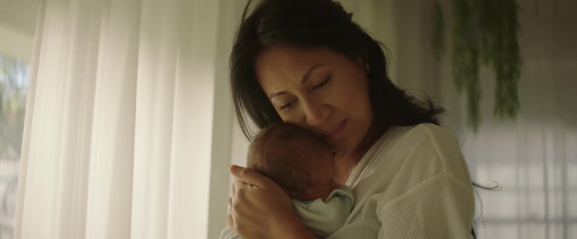 A mother is rocking her baby in her arms