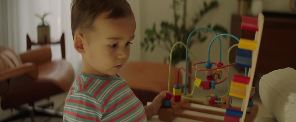 A male child playing with a cart causing it to fall over
