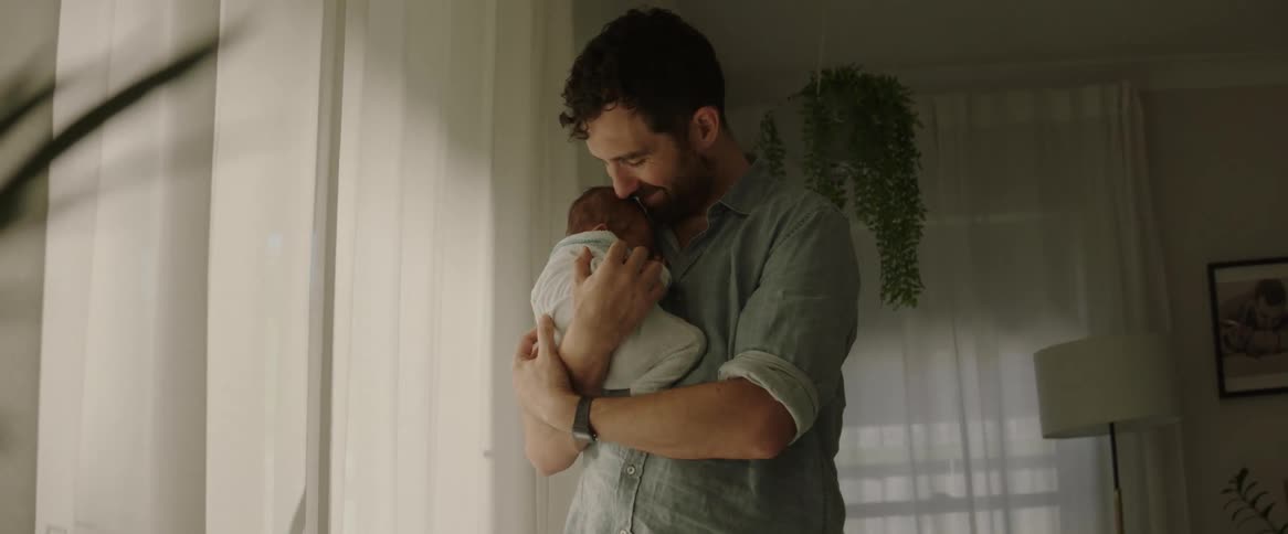 A man with his baby on his lap as he hugs and kisses him