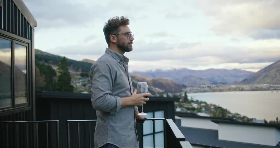 Man drinking a glass of wine on the porch of the house