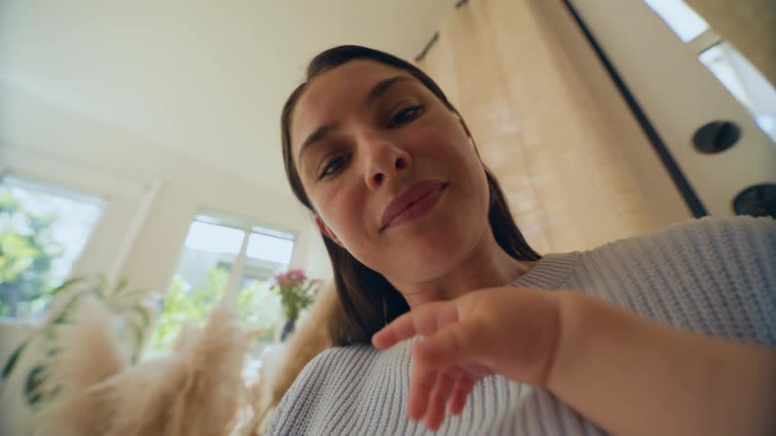 Close up point of view of a mother holding and making facial expression at a baby