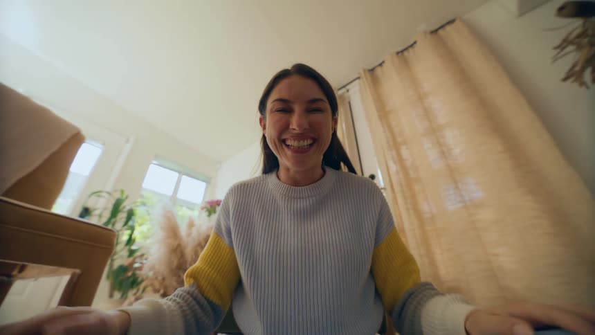 A woman wearing a sweatshirt playing by covering her face almost like playing with a child