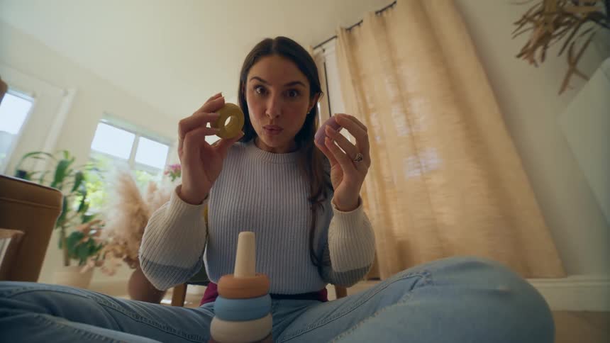 Point of view of a woman sitting on her floor playing with a ring toy and putting them up to her eyes playfully