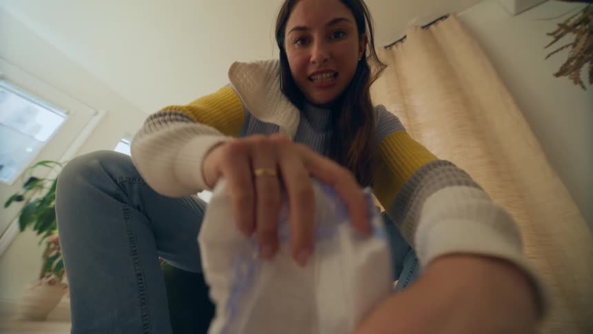 Seated woman talking on the phone while opening a paper