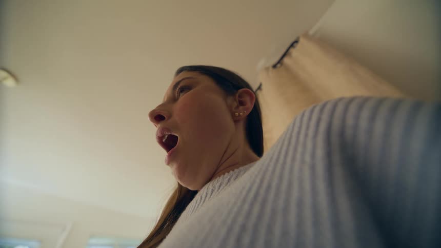 A mother with a baby in her arms yawns and smiles at the baby