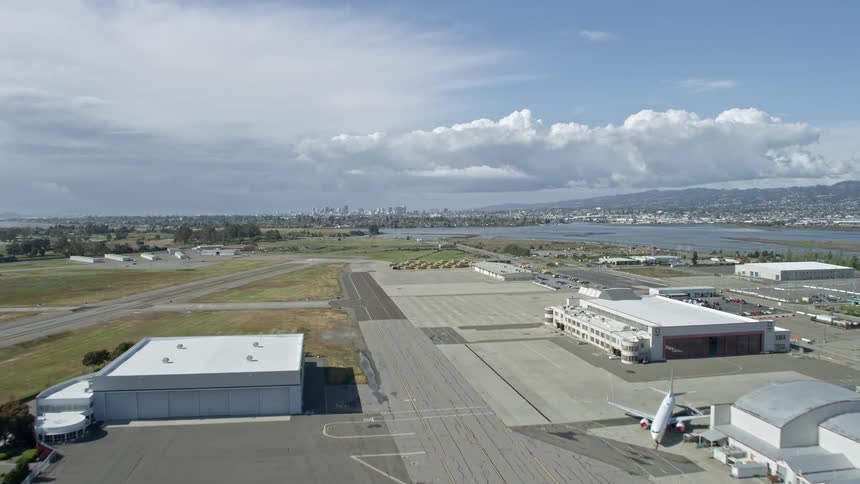 Aerial footage of flying over Oakland Airport towards the downtown skyline of Oakland California on a partly cloudy day