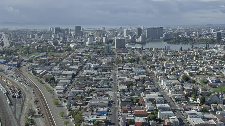 Aerial footage showcasing the bustling cityscape of Downtown Oakland and Lake Merritt as the camera tilts up from the 880 freeway