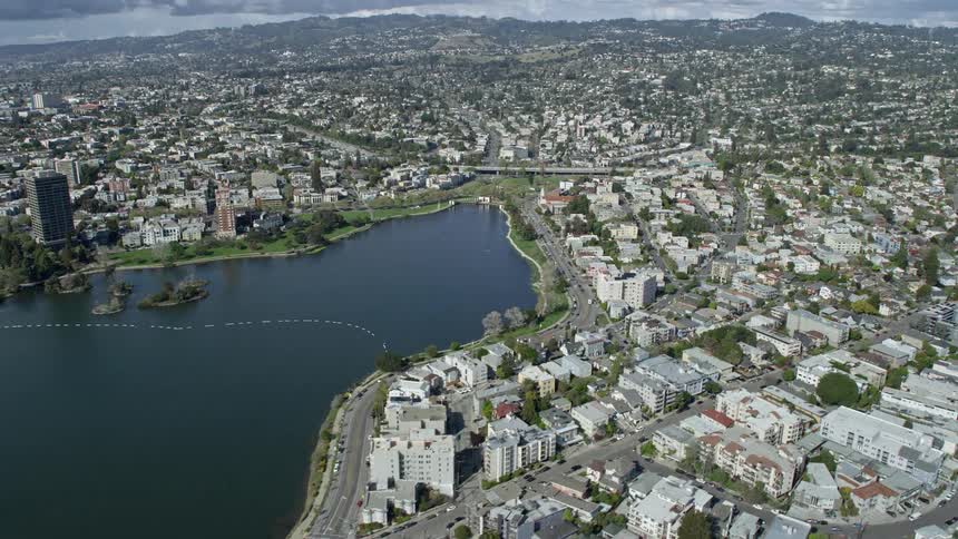  aerial stock footage showcasing lakefront apartment buildings in Oakland California with a clear view of Lake Merritt on a sunny day in the downtown area