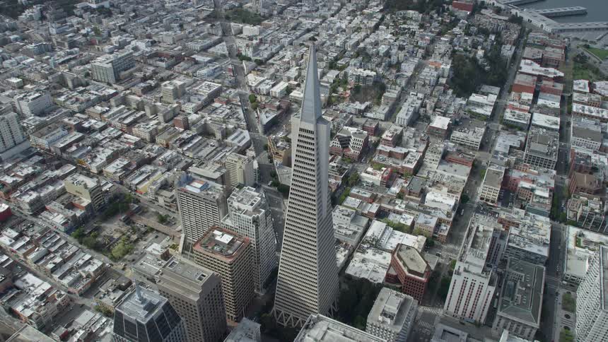  aerial footage of the iconic Transamerica Pyramid in downtown San Francisco California taken on a cloudy day as it is approached from a high-rise building capturing the city's skyline and superstructures