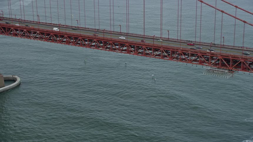 Aerial footage showcasing windsurfers enjoying water sports near the iconic Golden Gate Bridge on a cloudy day in San Francisco California