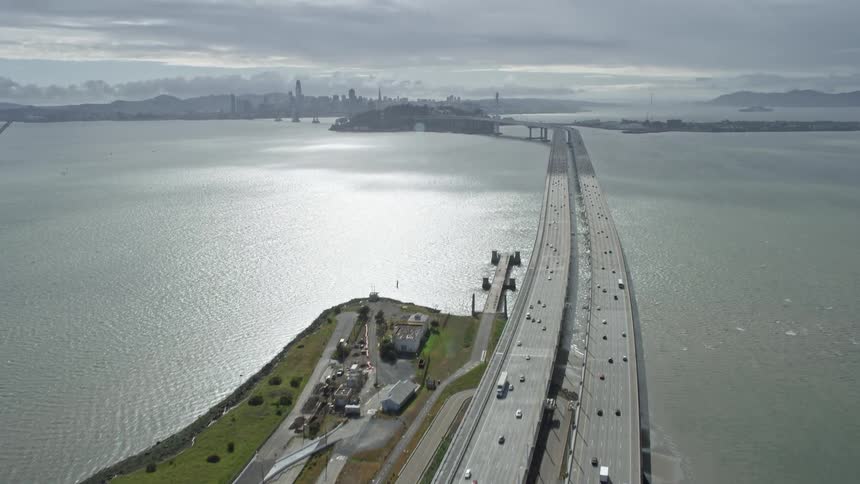 Aerial view of road bridge approaching Bay Bridge in Oakland California with light traffic and cloudy skies