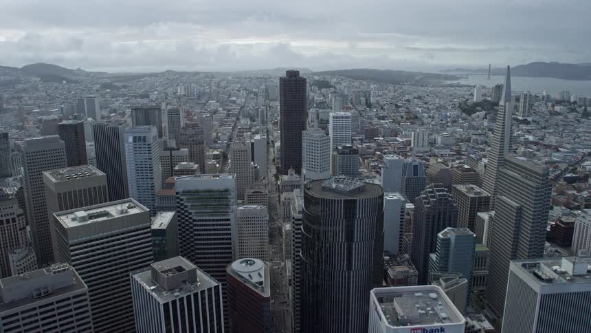  aerial footage flying over downtown San Francisco towards the iconic 555 California skyscraper showcasing the city's impressive skyline on a cloudy day