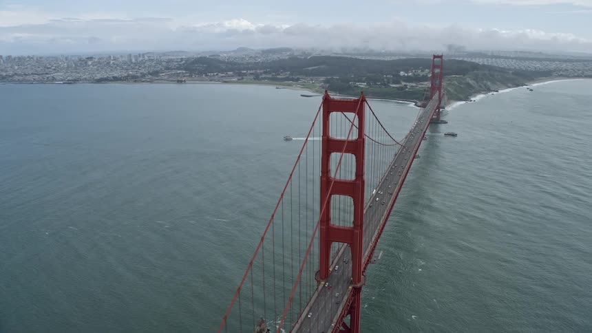  aerial footage of traffic traveling across the iconic Golden Gate Bridge spanning the strait on a cloudy day in San Francisco California