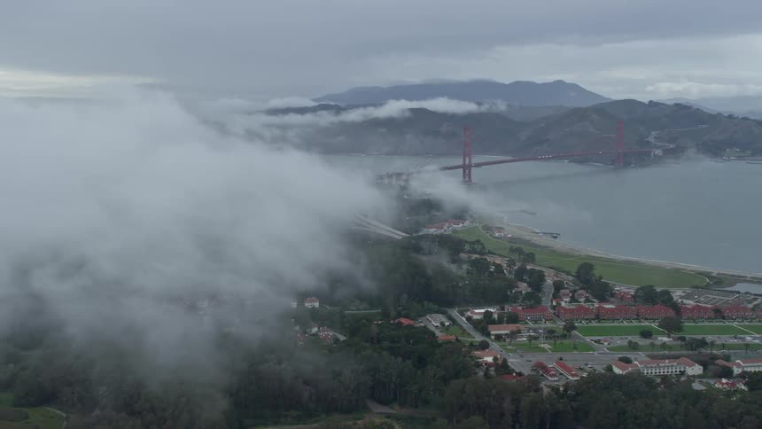 Aerial footage of the iconic Golden Gate Bridge emerging from a foggy bank showcasing the stunning views over The Presidio California