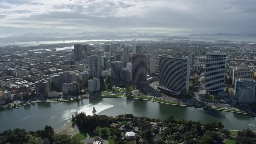  aerial footage showcasing downtown office buildings along the lakeside in Oakland California on a partly cloudy day
