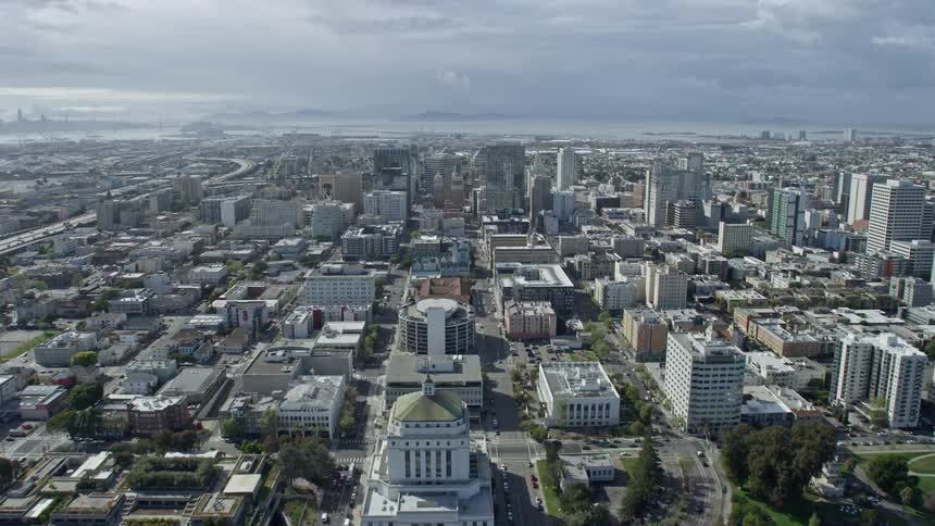 Aerial footage of flying over Downtown Oakland towards Tribune Tower in California during the day with partly cloudy skies
