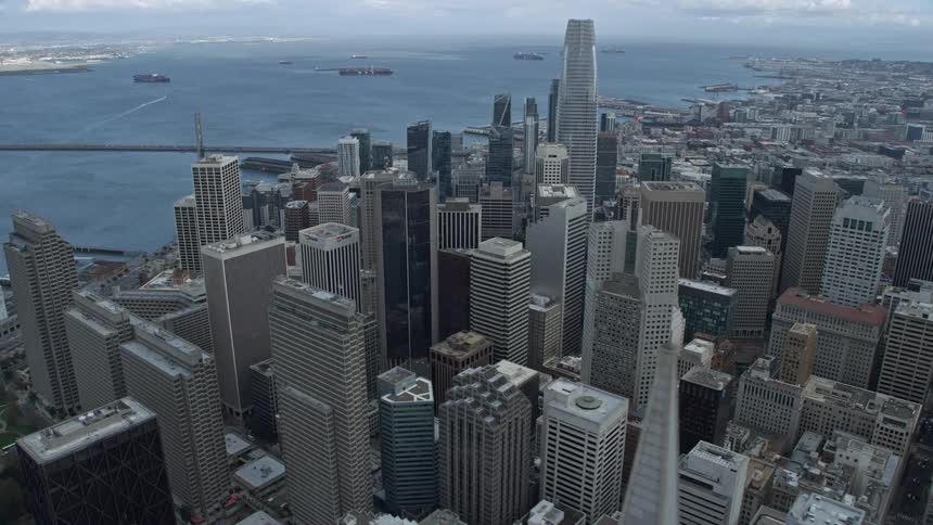  aerial footage of a side view flying past tall skyscrapers in Downtown San Francisco California showcasing the iconic Transamerica Pyramid and the city's downtown area on a cloudy day