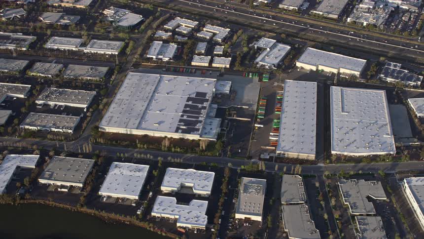 Aerial footage of warehouse buildings in Fremont California showcasing the urban area with roads and traffic during the day time