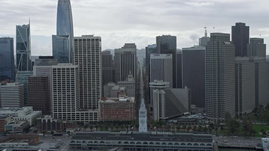  aerial footage revealing the iconic Ferry Building and Market Street in downtown San Francisco with a tilt up towards the city skyline and cloudy skies