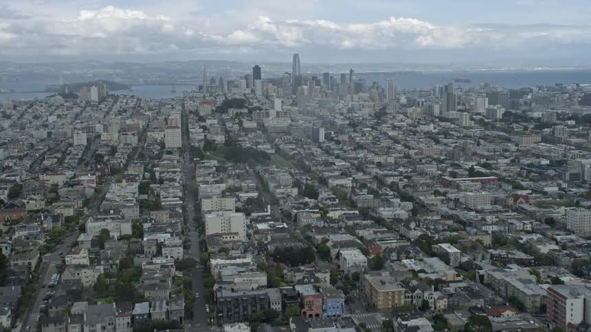  aerial footage flying through fog to reveal the San Francisco skyline showcasing the city's high rise buildings and downtown area on a partly cloudy day in Northern California