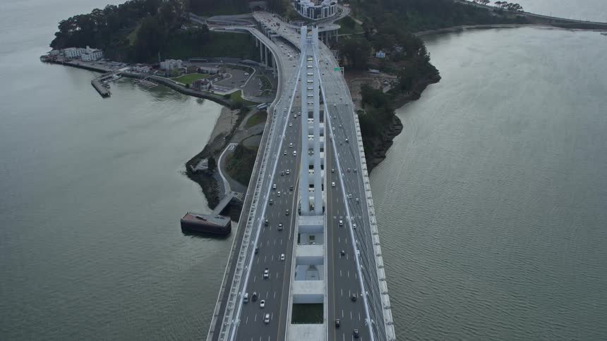 Aerial footage showing overhead view of traffic on the Bay Bridge in Oakland California with cloudy skies in the background