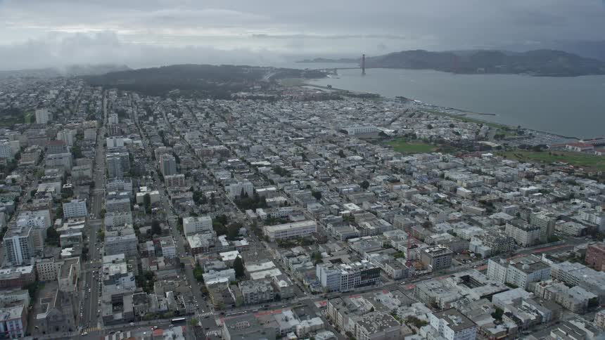 Aerial footage of approaching the Marina District neighborhood and the iconic Golden Gate Bridge on a cloudy day in San Francisco California