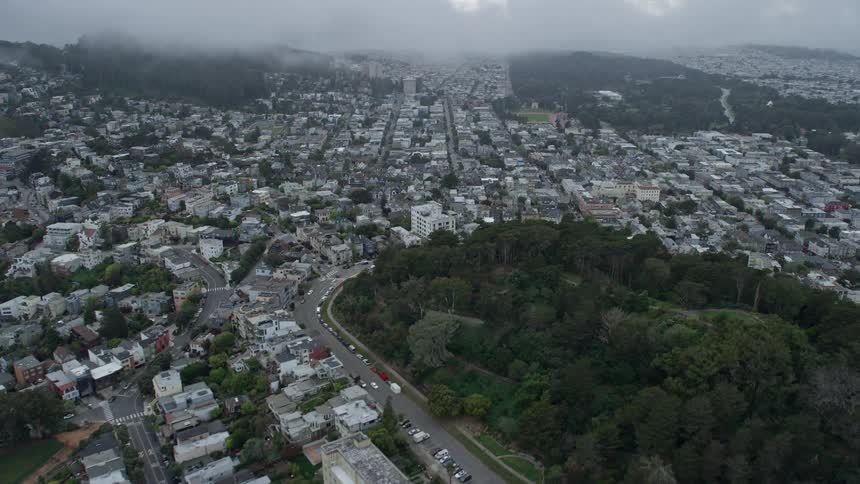 aerial footage showcases the scenic neighborhoods surrounding the hills captured under white clouds in the Castro District and Cole Valley of San Francisco California