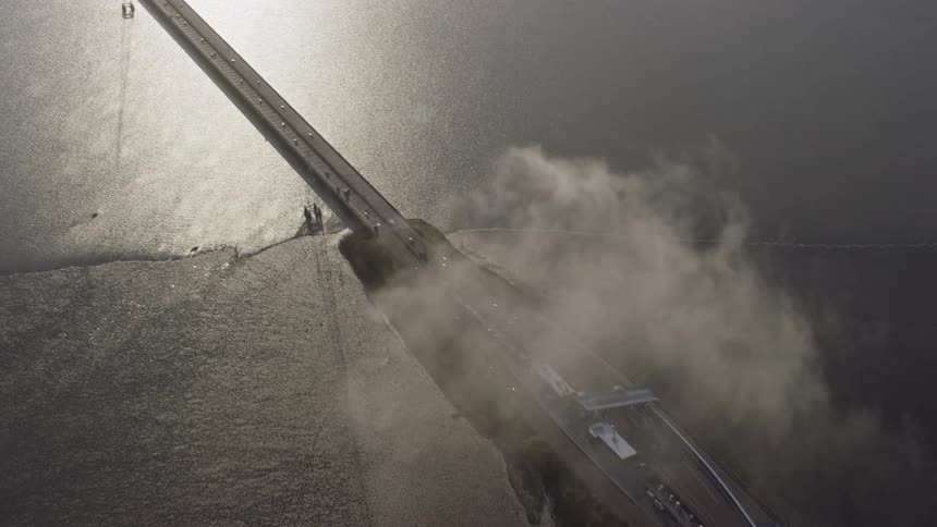 Aerial footage of the San Mateo Bridge in Hayward California revealing toll booths as the camera flies away