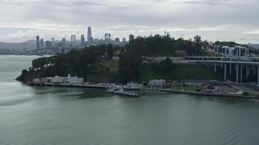  aerial footage of the Coast Guard pier on Yerba Buena Island California showing an approach to the dock with cloudy skies and a side view perspective