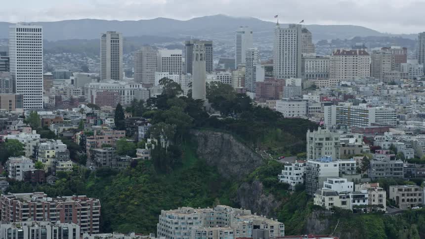  aerial footage of flying past the iconic Coit Tower in North Beach San Francisco capturing the beauty of the city and its cloudy skies during the day