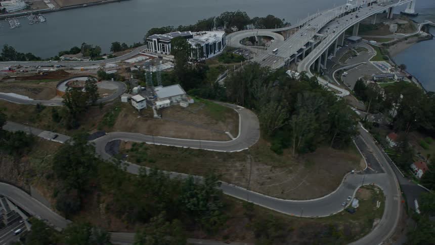 Aerial clip flying over Yerba Buena Island and the Bay Bridge approaching from a side view with cloudy skies in California's Bay Area