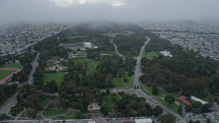  aerial footage capturing a side view of Golden Gate Park under a foggy sky showcasing the iconic structure of San Francisco California on a spring/summer day