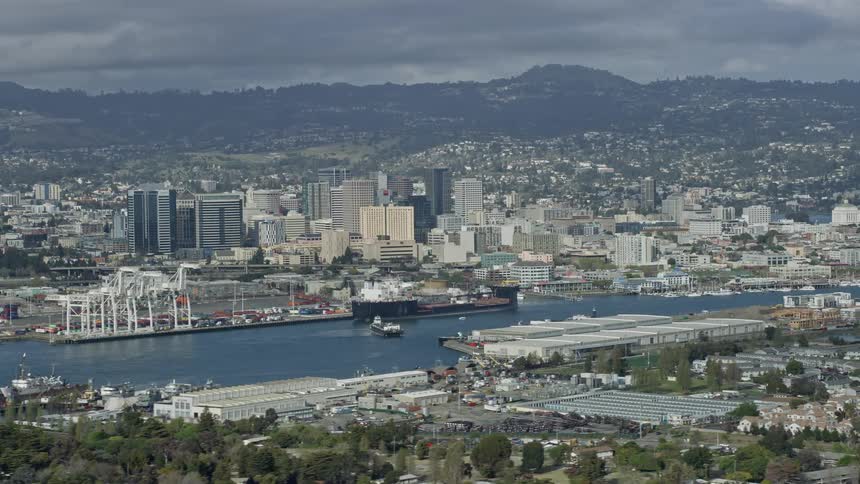  aerial footage of Downtown Oakland California on a partly cloudy day showcasing the wide angle view of the city's downtown area and the Oakland Inner Harbor captured with a Shotover F1 gimbal system providingand cinematic perspective during the summer se
