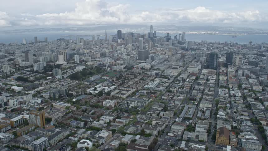 Aerial view of Western Addition neighborhood in San Francisco tilting up to reveal the downtown skyline on a sunny day