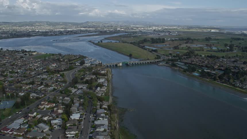Aerial view of waterfront homes in a coastal suburban town in Alameda California flying towards Oakland Airport on a partly cloudy day