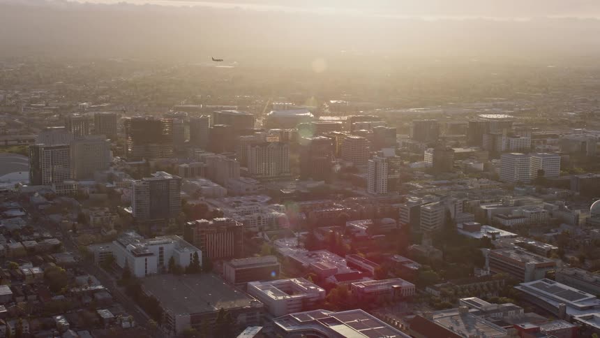 A stunningaerial view of a plane gracefully soaring over the captivating Downtown San Jose at sunset showcasing the vibrant California city in all its magnificence