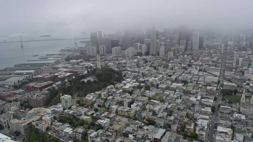 Aerial footage of foggy day in San Francisco showcasing Coit Tower and downtown skyscrapers