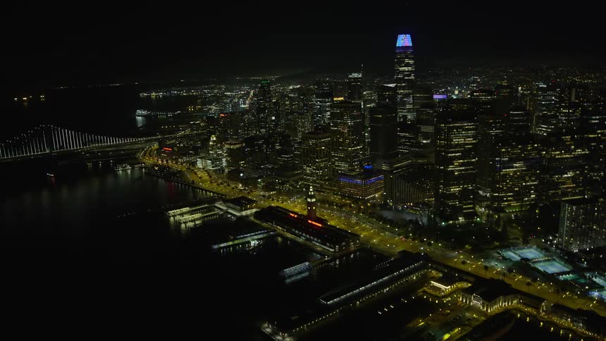 A stunningaerial footage of the Ferry Building at night showcasing the mesmerizing downtown San Francisco skyline with clear skies and towering skyscrapers