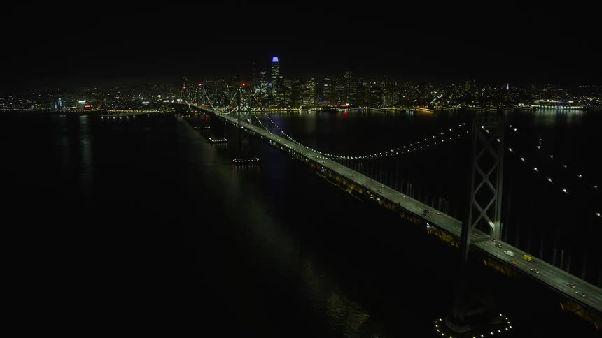 A mesmerizingaerial view of the Bay Bridge at night approaching Downtown San Francisco showcasing the city's stunning skyline and the clear skies of Northern California