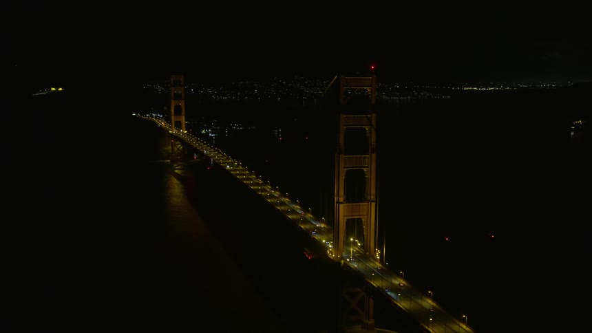 Aerial footage at night of the iconic Golden Gate Bridge in California showcasing its historic landmark status and light traffic
