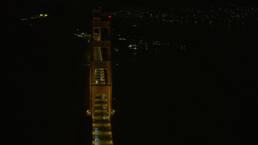  aerial footage of a nighttime view of the iconic Golden Gate Bridge in California with clear skies and light traffic as seen from a side view