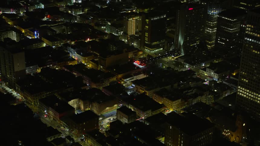 A stunningaerial footage of San Francisco's Chinatown at night showcasing illuminated office and apartment buildings against the backdrop of clear skies and the city's vibrant night atmosphere