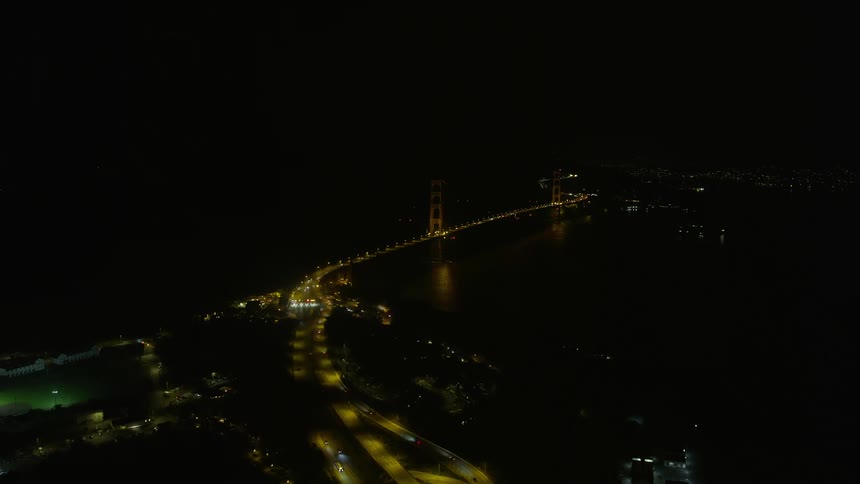  aerial footage capturing the approach to the iconic Golden Gate Bridge from Presidio at night in San Francisco Bay California showcasing clear skies and the historic landmark