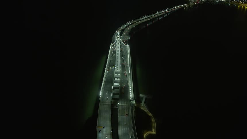 Aerial footage at night captures a stunning bird's eye view of cars traveling on the Bay Bridge in Oakland California as they approach the city