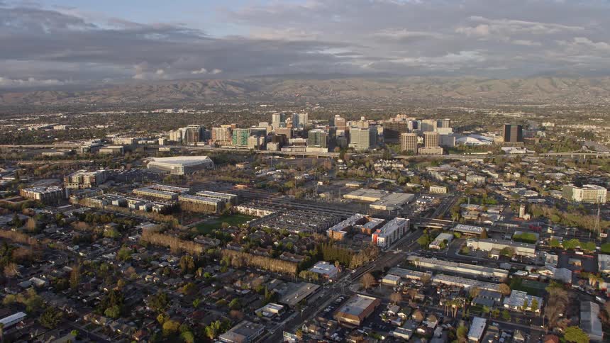  aerial footage capturing the majestic approach to Downtown San Jose at sunset revealing the hazy cityscape of Northern California's Bay Area