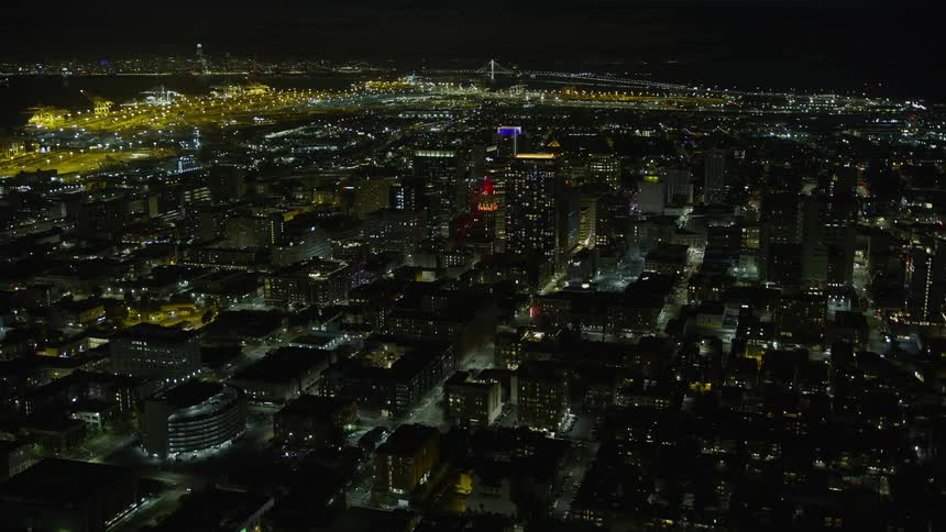  aerial footage showcasing the vibrant cityscape of Downtown Oakland at night featuring the iconic Tribune Tower and other office buildings with clear skies and a bustling urban atmosphere