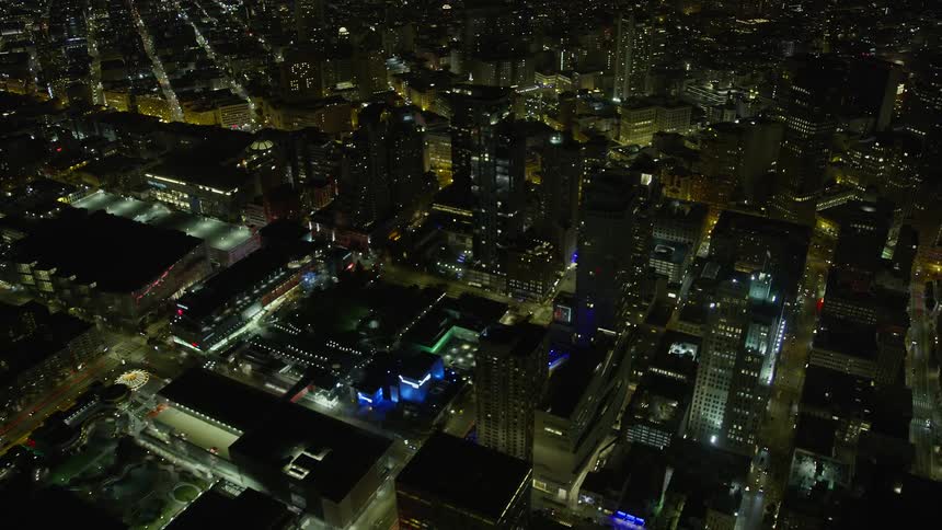 Fly away from the bright and tall skyscrapers of Downtown San Francisco at night capturing the stunning cityscape of Northern California