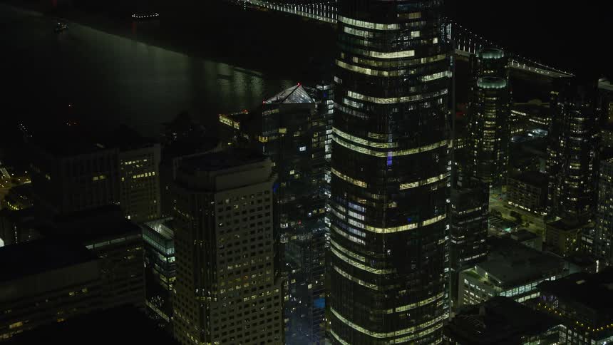 A stunningaerial footage showcasing the iconic Millennium Tower and Salesforce Tower in Downtown San Francisco at night with clear skies and a mesmerizing city skyline shot in the Bay Area during summer